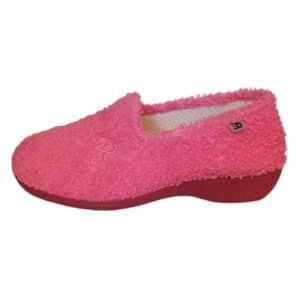 Vista lateral de la zapatilla rosa con cuña baja, mostrando un bordado decorativo en el lateral y el forro interior de puntos blancos.